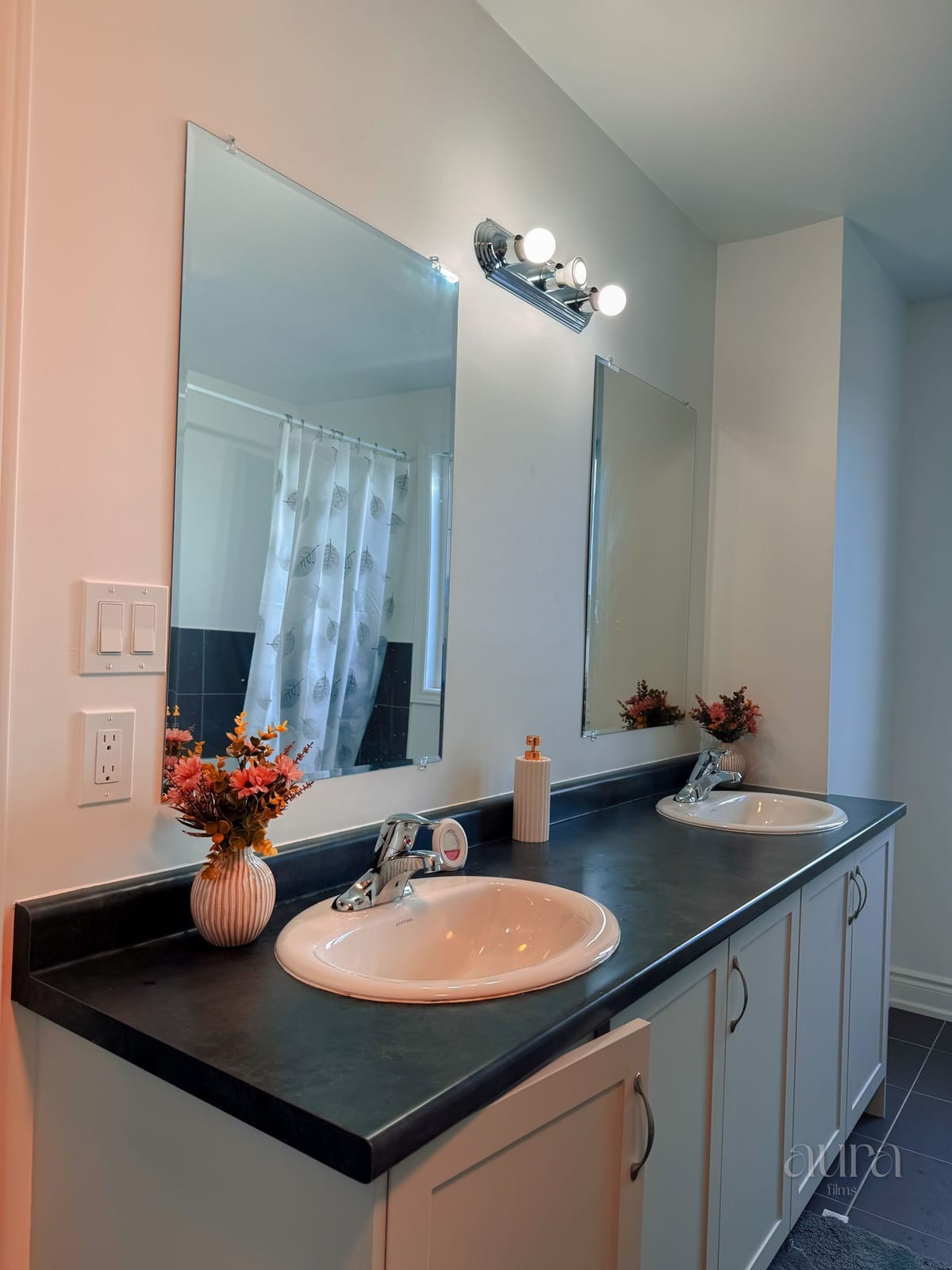 A bathroom with a dark stone vanity and warm lighting