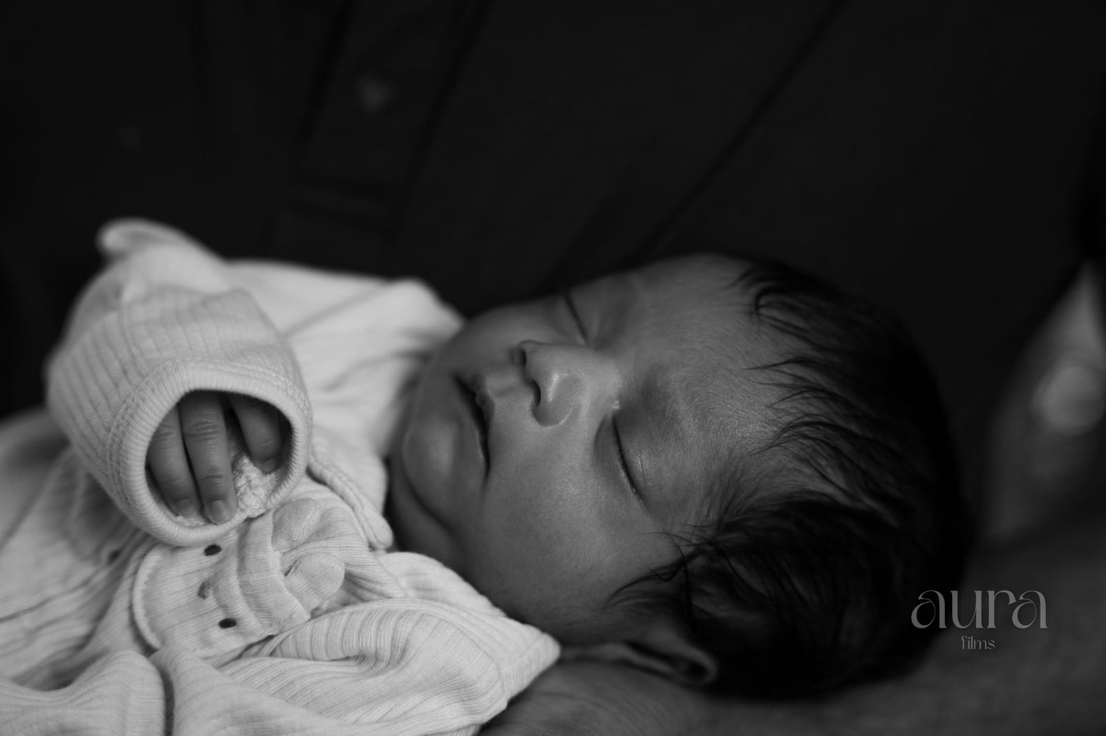 A newborn asleep in a soft knit, in black and white