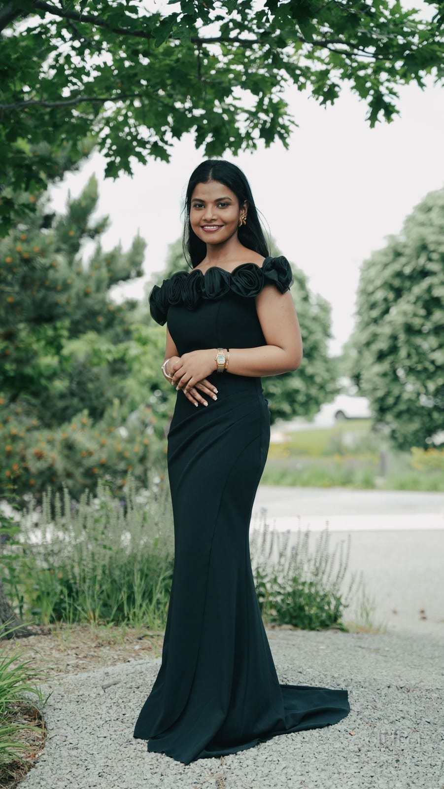 A woman in a deep green gown stands in a summer garden