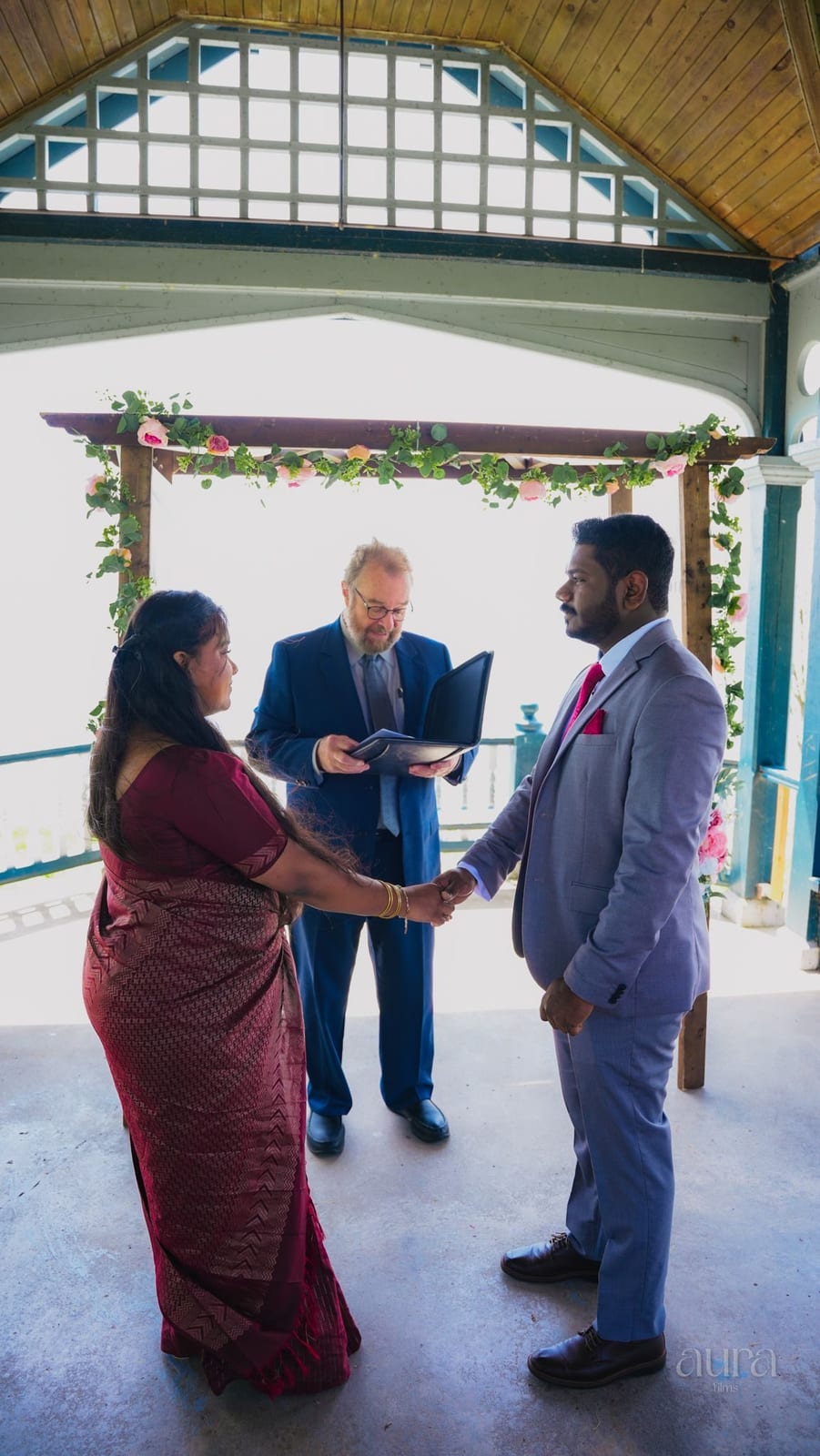 A couple exchange vows beneath a lakeside gazebo